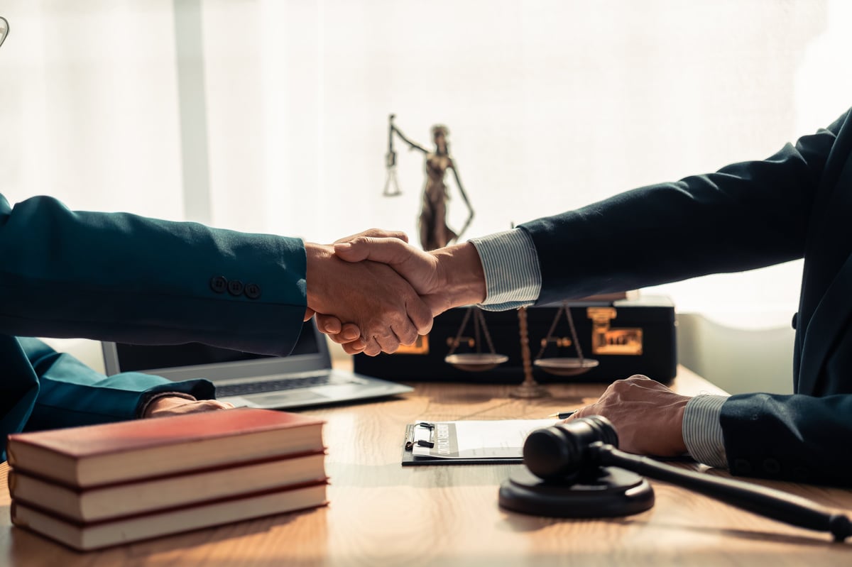 Lawyer and client shaking hands across a table in a legal office